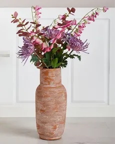 Terracotta vase med kunstige blomster i lyserøde og lilla nuancer