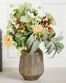 Fyldig smuk buket af kunstige blomster og bladgren i sarte farver i en flot metalvase