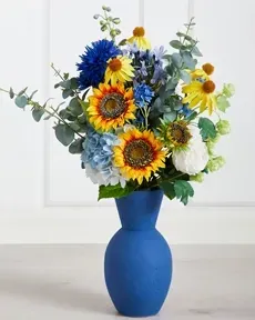 Flot buket af kunstige blomster i blå og gule nuancer i blå vase