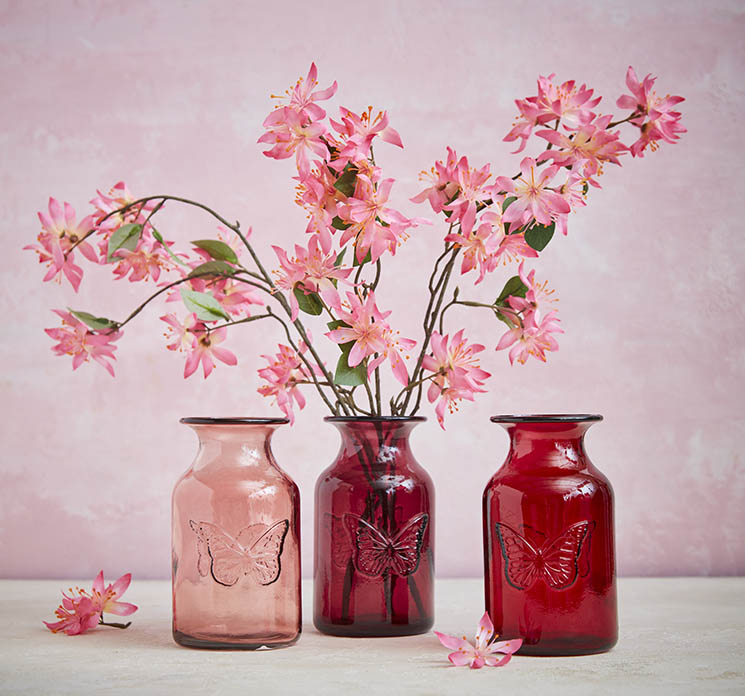 Klematis kunstig blomst af plast i pink vist med tre små fine glasvaser med sommerfugle motiv