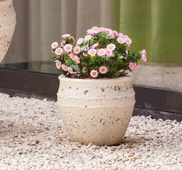 Marguerit buket af kunstige blomster i lyserøde i plast uv-beskyttet 28cm vist i havemiljø