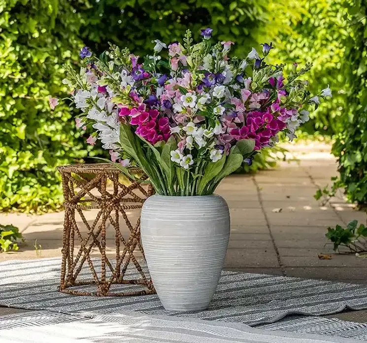 Kunstige klokkeblomster i lilla vist i stor vase med andre klokkerblomster