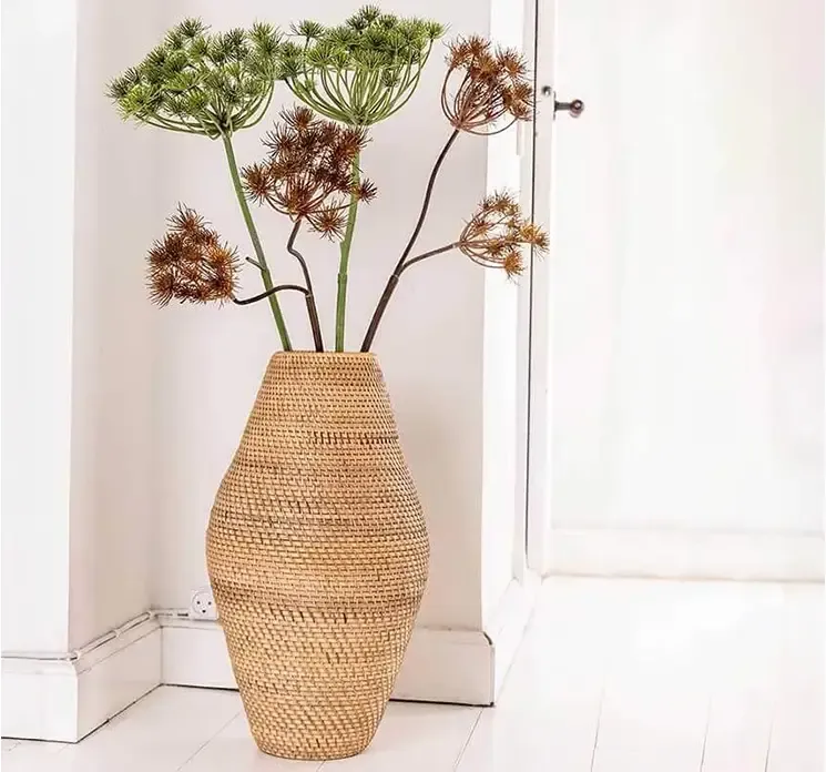 Vase af rattan i natur farve vist i entre med kunstige bjørnekløer