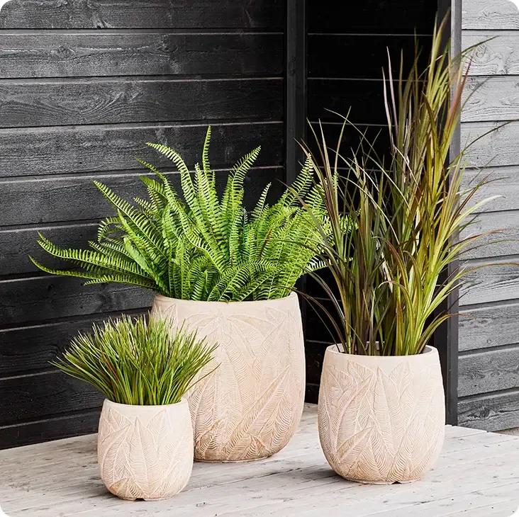 Bregne og græs af plast uv-beskyttet i krukker vist i terrasse miljø, kunstige planter