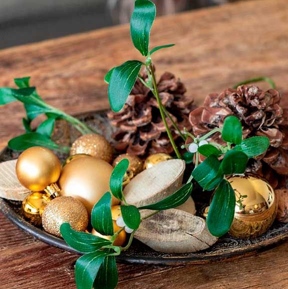 Fad med gyldne julekugler, mistelten, kogler