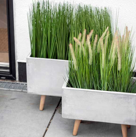 Græsser i cementkrukker på træben