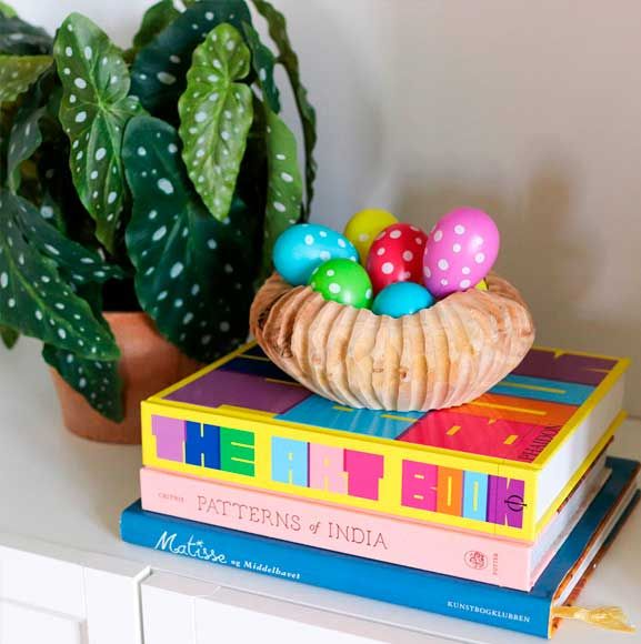 Farverige påskeæg i træskål med kunstig plante