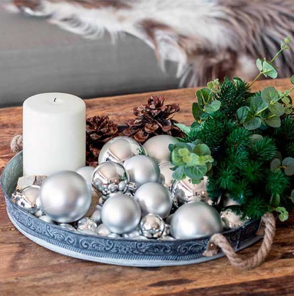 Juledekoration med sølv julekugler, stearinlys og kunstig eucalyptus