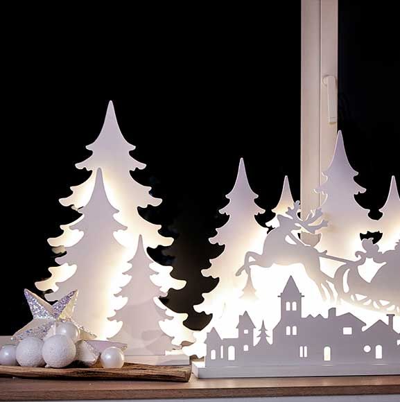 Vinterdekoration i vinduet med hvide juletræ