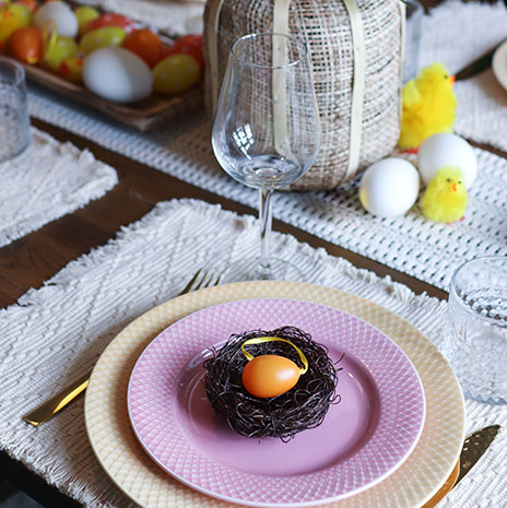 Fuglereder og æg af plast sat på tallerken på et påskedækket bord