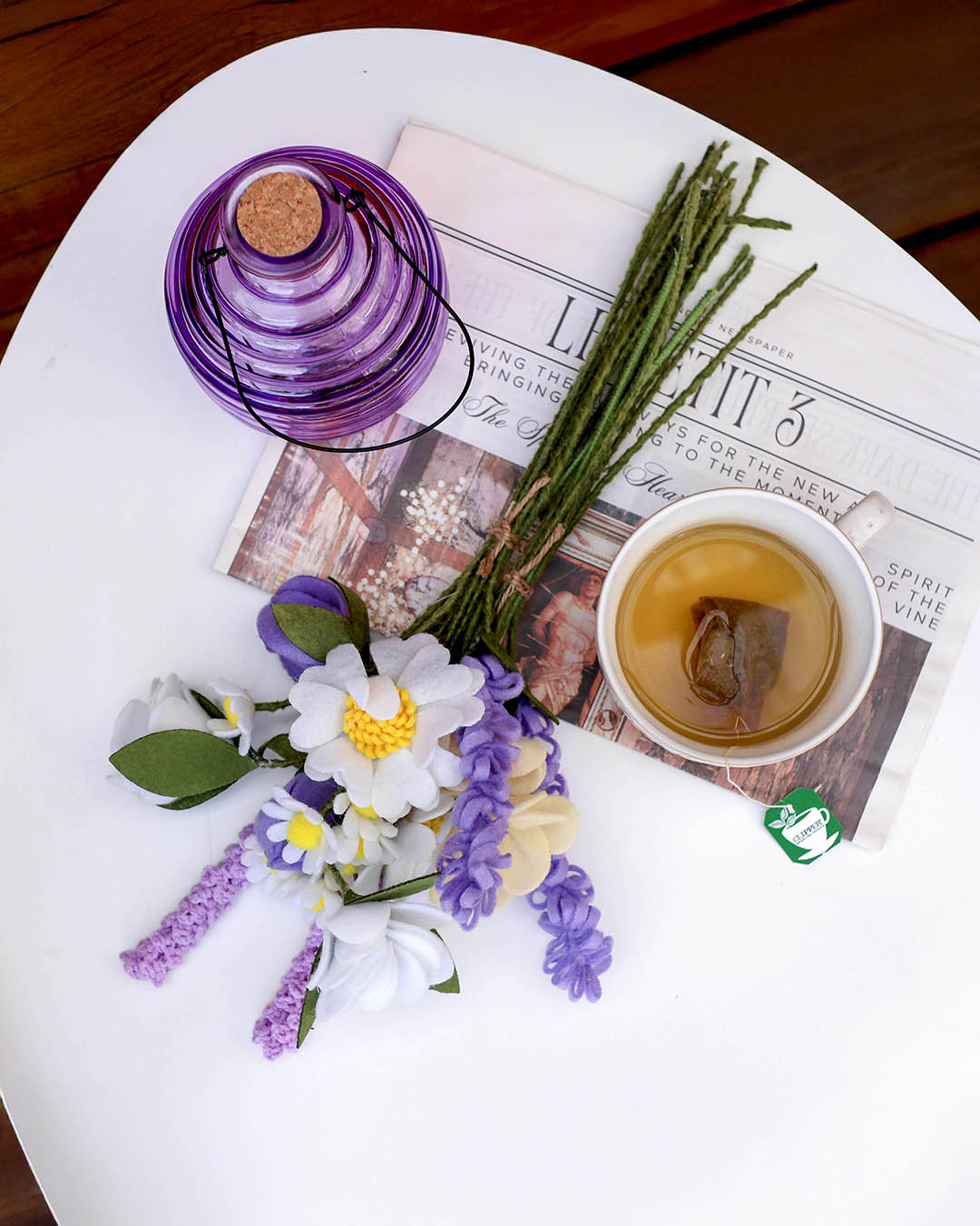 Fin blomsterbuket af stof vist på et havebord med hvepsefanger og en kop te