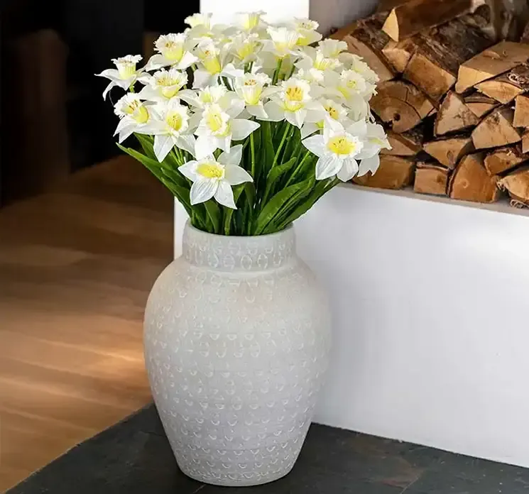 Terracotte vase med mønster i creme farvet vist i stuemiljø med kunstige påskeliljer