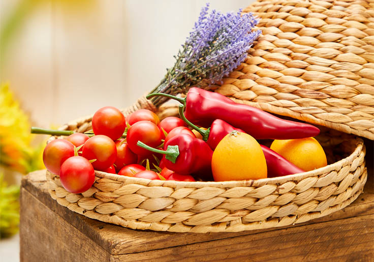 Kunstige grøntsager i flot flettet fad med låg