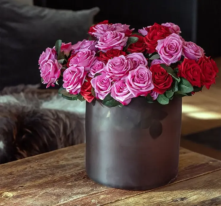 Kunstig rosen buket af kunststof i rød vist i vase sammen med kunstig rosen buket i lyserød i glasvase på sofabord