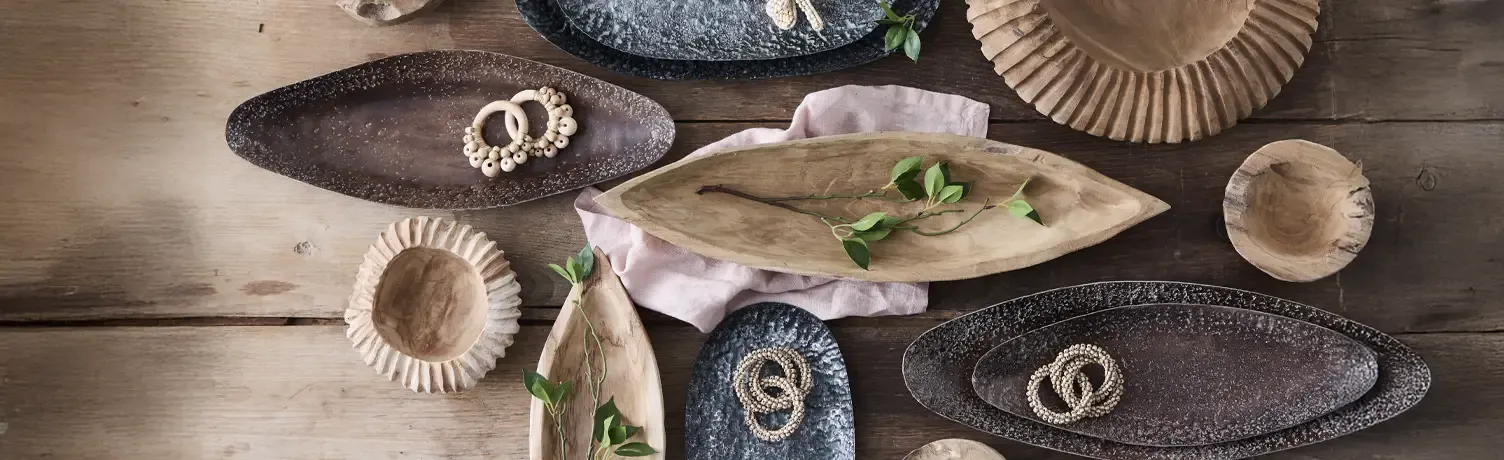 Forskellige fade og skåle i metal og træ vist på en bordplade