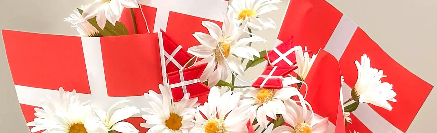 Flag på pind og flagguirlander sammen med kunstige margueritter