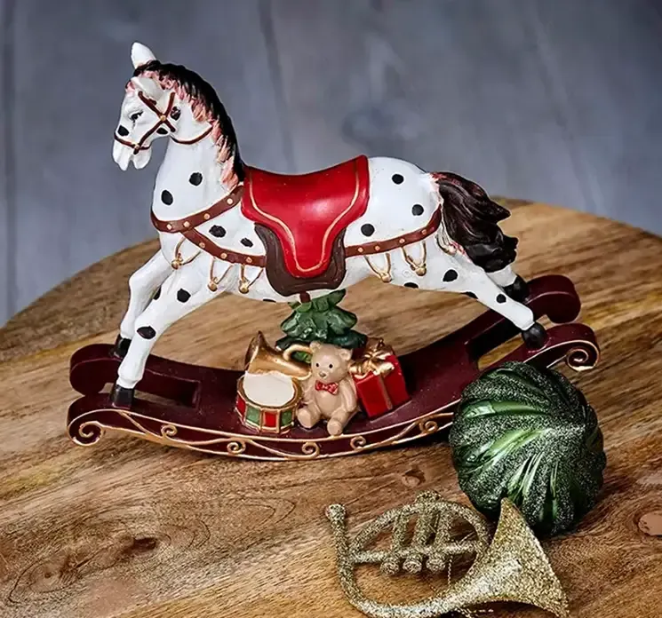 Gyngehest af plast multifarvet til dekoration vist på træbord med juleornamenter