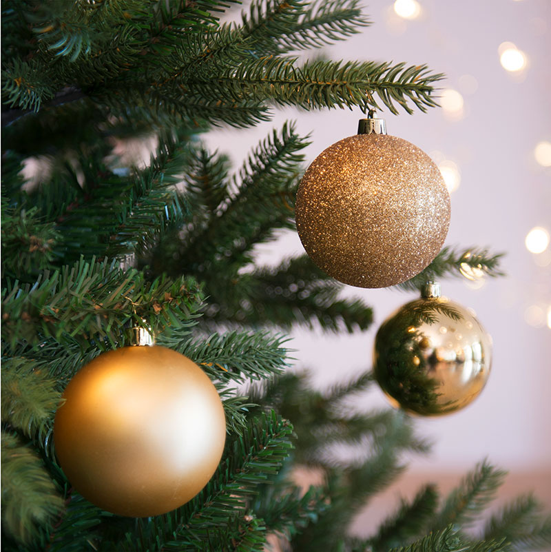julekugler af plast i guldfarvet, mat, blank og med glimmer vist på juletræ