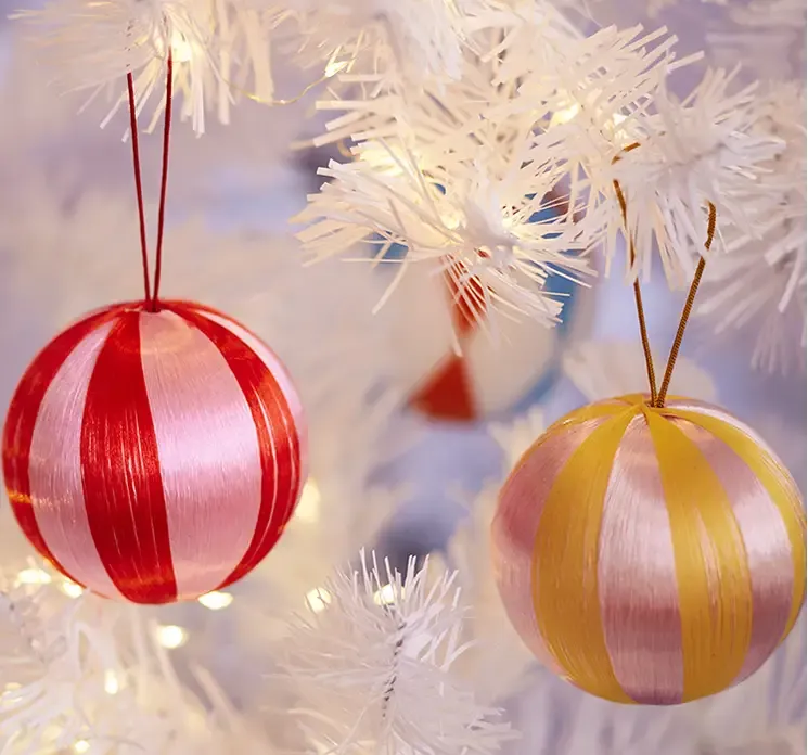 Julekugle med mønster af plast i pink og rød vist hængende på træ