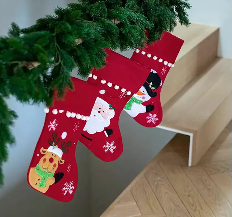 Julesok i rød af filt med snemandsmotiv vist med andre julesokker hængt op på trappe