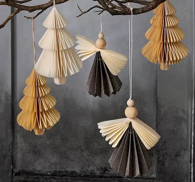 Engel med ophæng af pap i mørkegrå juletræspynt vist i miljø hængende fra en gren