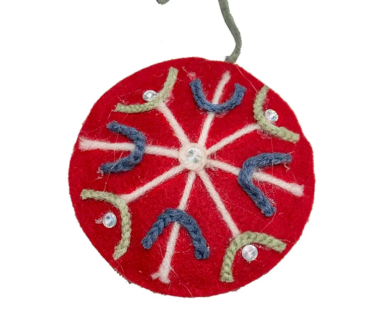 Filt kugle i rød med pynt på en side, kuglen er flad og med snor til at hænge op