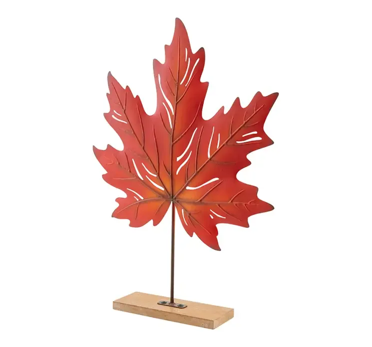Kunstig ahorn blad i rød af metal på stilk sat på træfod