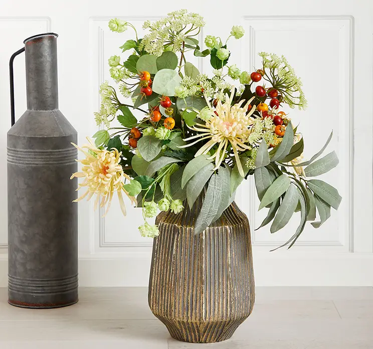 Krysantemum kunstig blomst af plast i creme farvet vist i buket med andre kunstige blomster og grene på gulv i stue