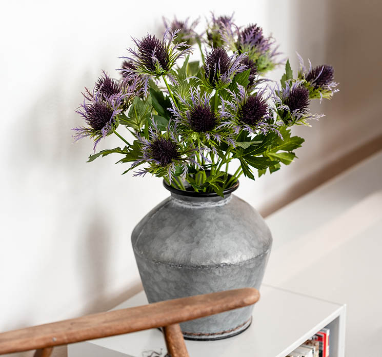 Tidsel kunstig blomst i lilla vist i zink vase i stuemiljø