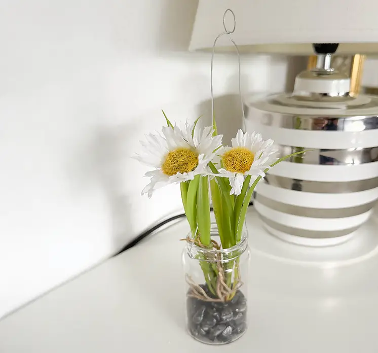 Marguerit kunstig blomst i hvid sat i glas vase med små sten og ophæng