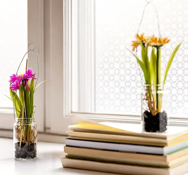 Kunstige margueritter i glaskrukke med kunstig jord, til ophæng sat i vindueskarm