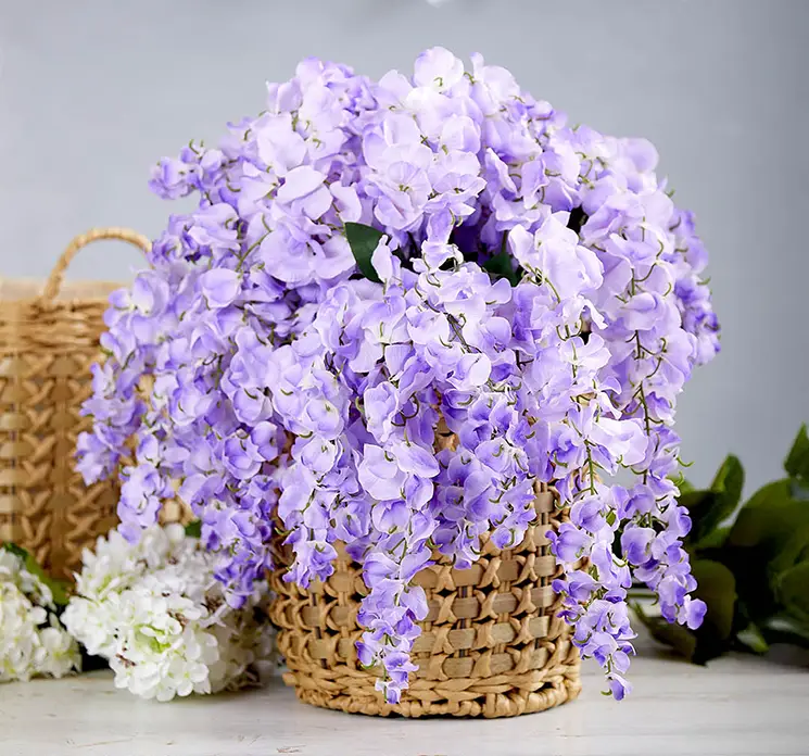 Wisteria også kaldet blåregn af plast i lilla, kunstig blomst vist i miljø sat i en flettet kurv