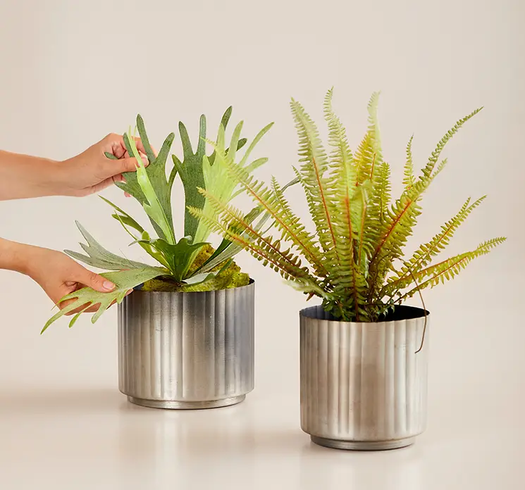 Bregne på stilk kunstig plante af plast i grøn 40cm vist på bord med kunstig hjortetaksplante i krukker
