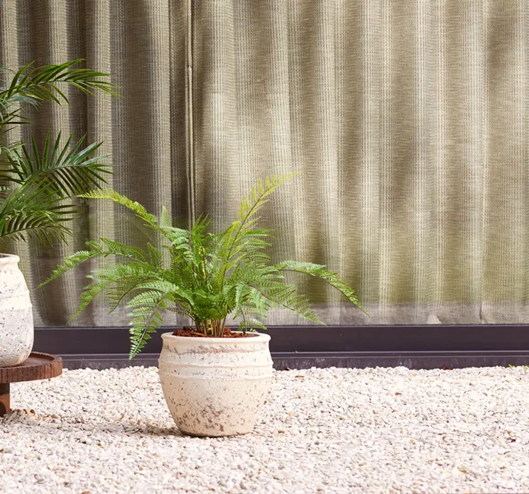 Bregne kunstig uv-beskyttet plante vist i krukke på terrasse
