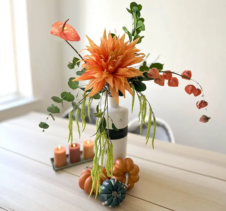 Dahlia, ananaskirsebærgren, flamingo blomst og amarant sat sammen til en fin efterårsbuket på et spisebord