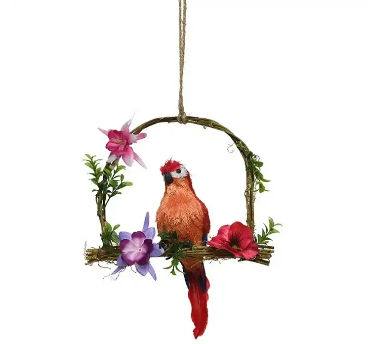 Kunstig multifarvet papegøje med gåsefjer der sidder på en gynge med små kunstige blomster
