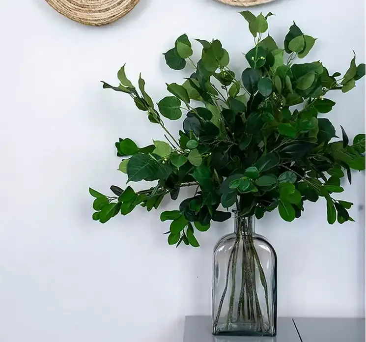 Kunstig hellig figen gren i grøn af plast vist i miljø med klar glas vase