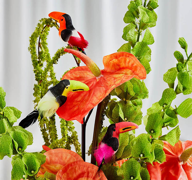 Kunstige tukan på klips sat på kunstige flamingo blomster i buket