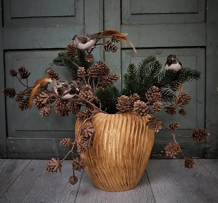 Gren kunstig gran af plast i grøn model nisse vist i vase af teaktræ med grene og kunstige fugle i miljø