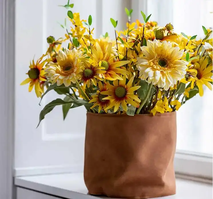 Gerbera kunstig blomst af plast i gul 48cm vist i læderkrukke i vindueskarm