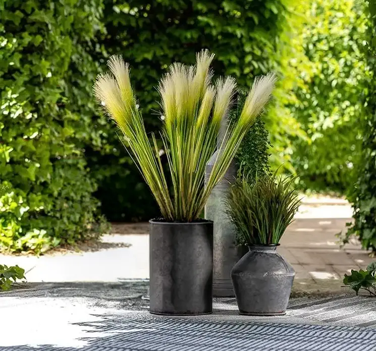 Pampas kunstig græs af plast i grøn og hvid vist i vase på terrasse