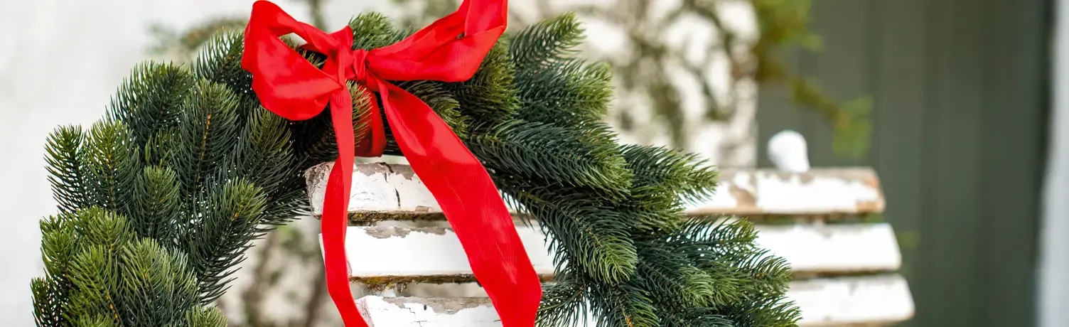 kunstig grankrans med rødt sløjfe af taftbånd