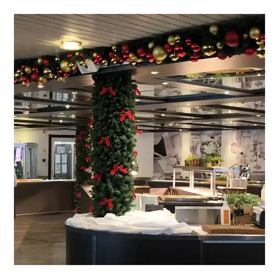 Granranke model Imperial kunstig af plast i grøn Ø25c30m vist pyntet op med forskellige julekugler og sløjfer på restaurant