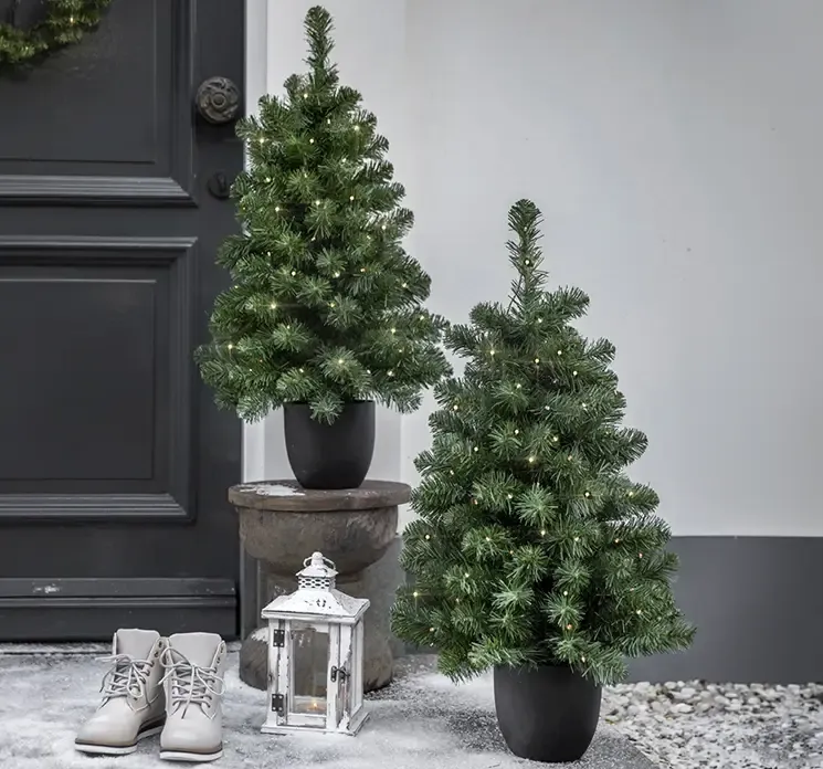 Grantræ Imperial kunstigt med LED lys i potte til ude og indendørs brug af PVC i grøn vist ved hoveddør udendørs