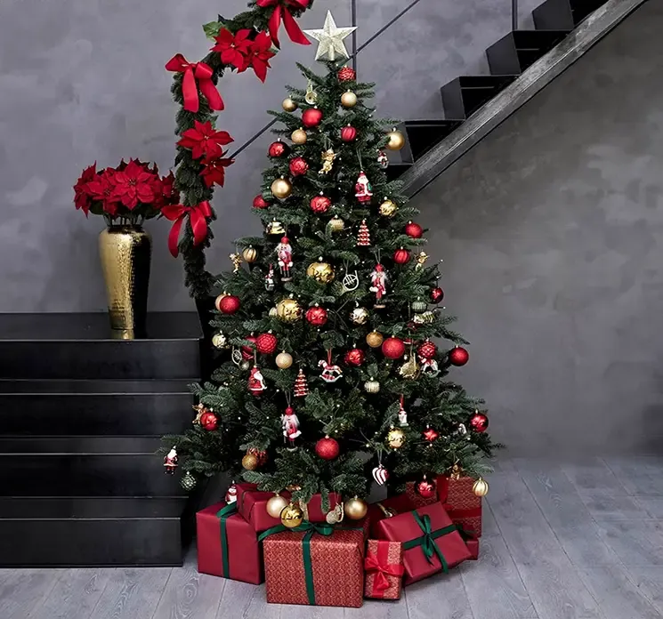 Kunstig gran juletræ grandis af plast i grøn med LED lys vist i miljø med julekugler af plast i guld og rød