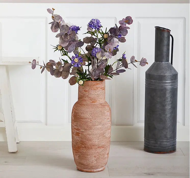 Eukalyptus kunstig gren af plast i lilla vist i vase på gulv i stuemiljø