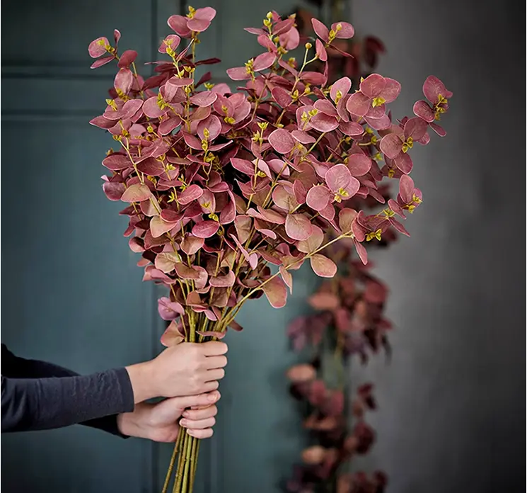 Eukalyptus kunstig gren af plast i rosa farvet 86cm vist flere sammen i en buket holdt i hånd