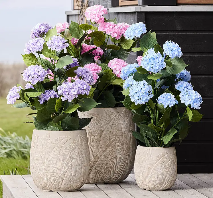 Hortensia kunstige blomster med uv-beskyttelse vist i krukker i havemiljø