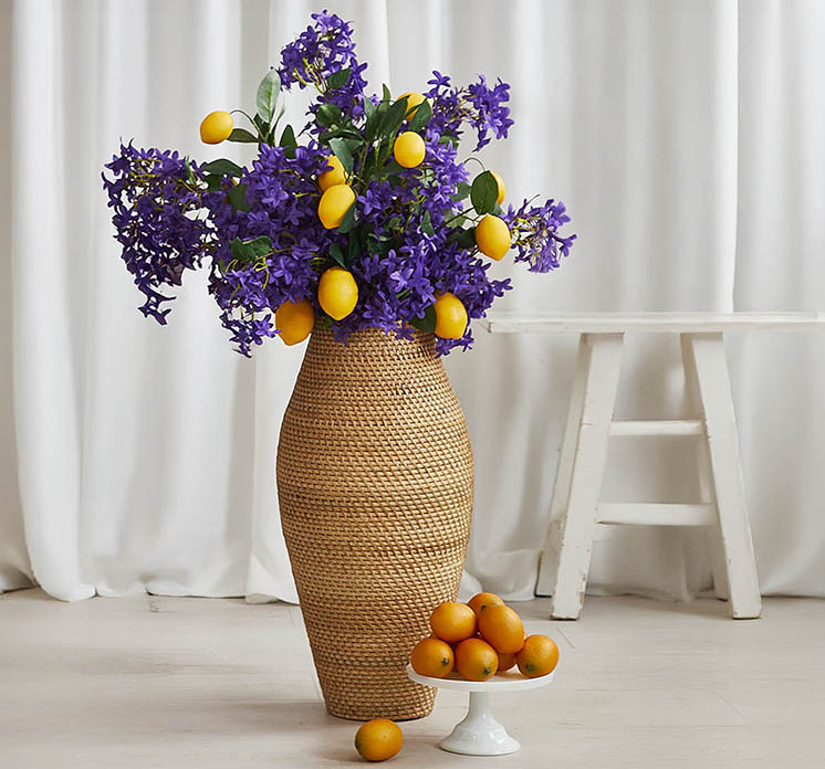 Jasmin kunstig blomst af plast i lilla sat i flettet gulv vase med kunstige citrongrene i stuemiljø