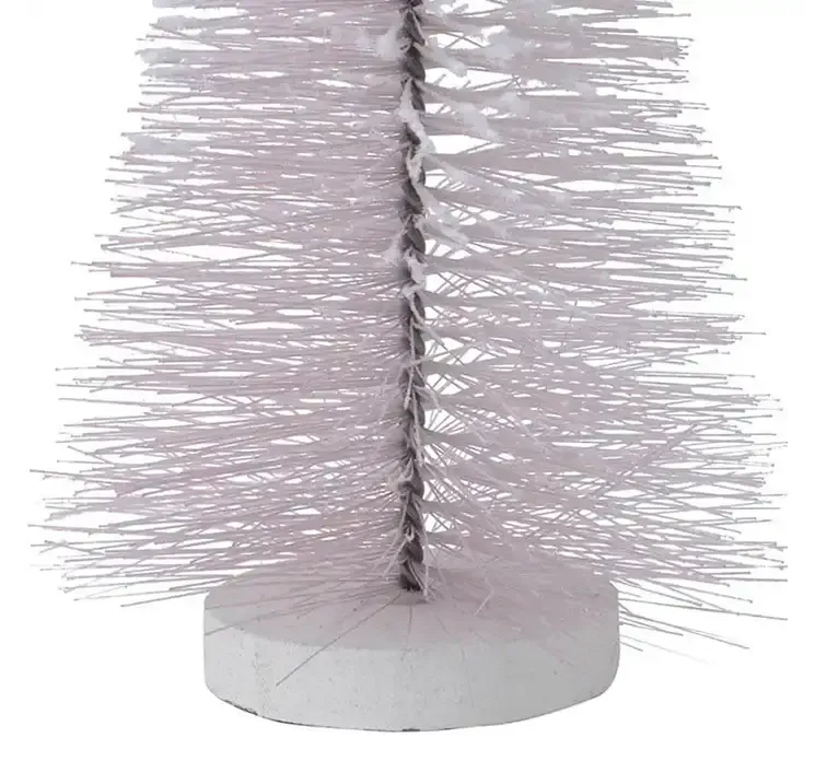 Kunstig børste juletræ af plast i lyserød på hvid træplade closeup